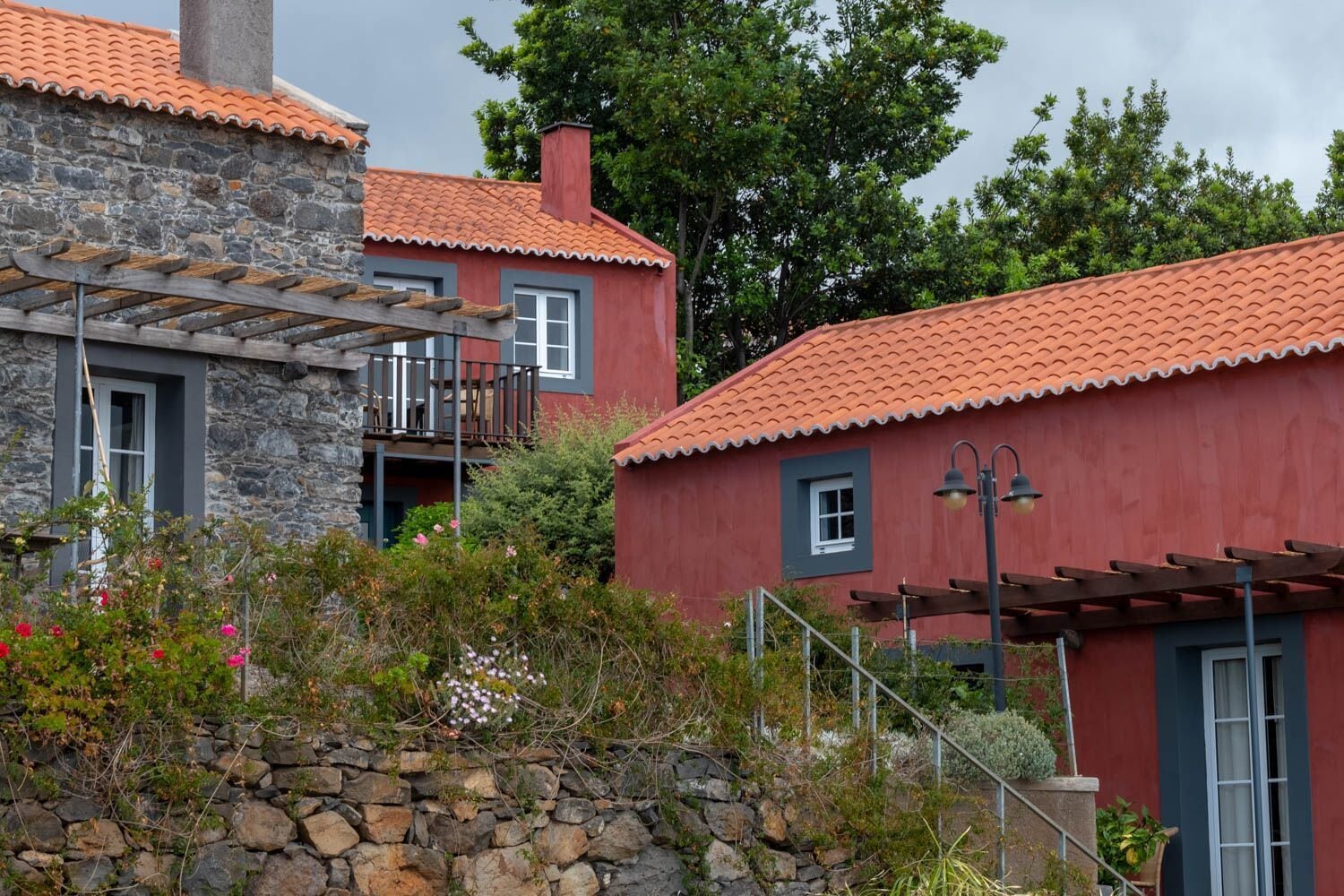 A stone building with a red-tiled roof and a wooden balcony.