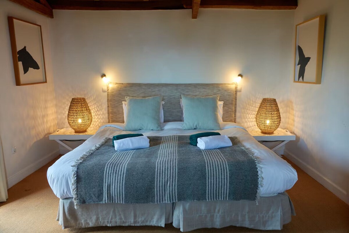 A neatly made bed with a striped blanket, two pillows, and two bedside lamps.