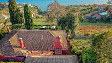 A residential area with a red-roofed house, a garden, and a view of the sea.