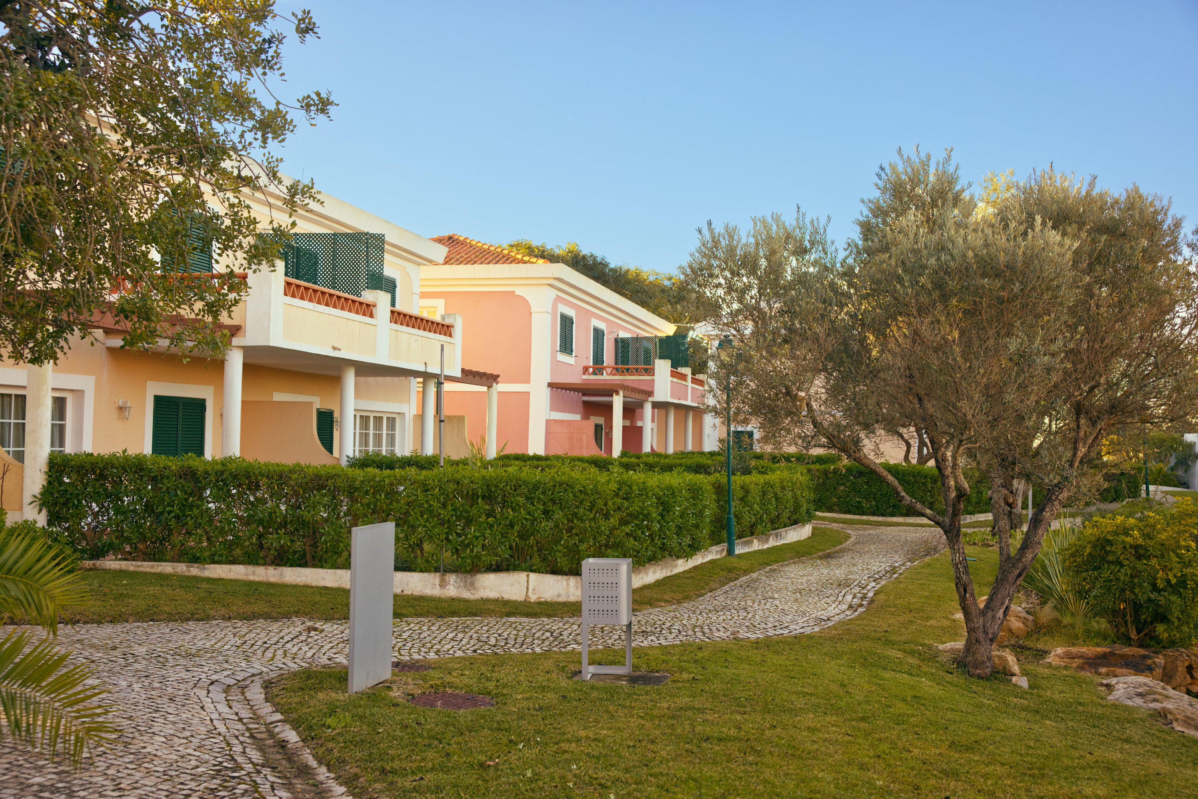 A residential building with a paved driveway, a well-maintained lawn, and a tree.