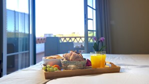 A breakfast tray with croissants, grapes, strawberries, and orange juice on a bed with a view of a balcony. - Cegonha Country Club (Loulé)