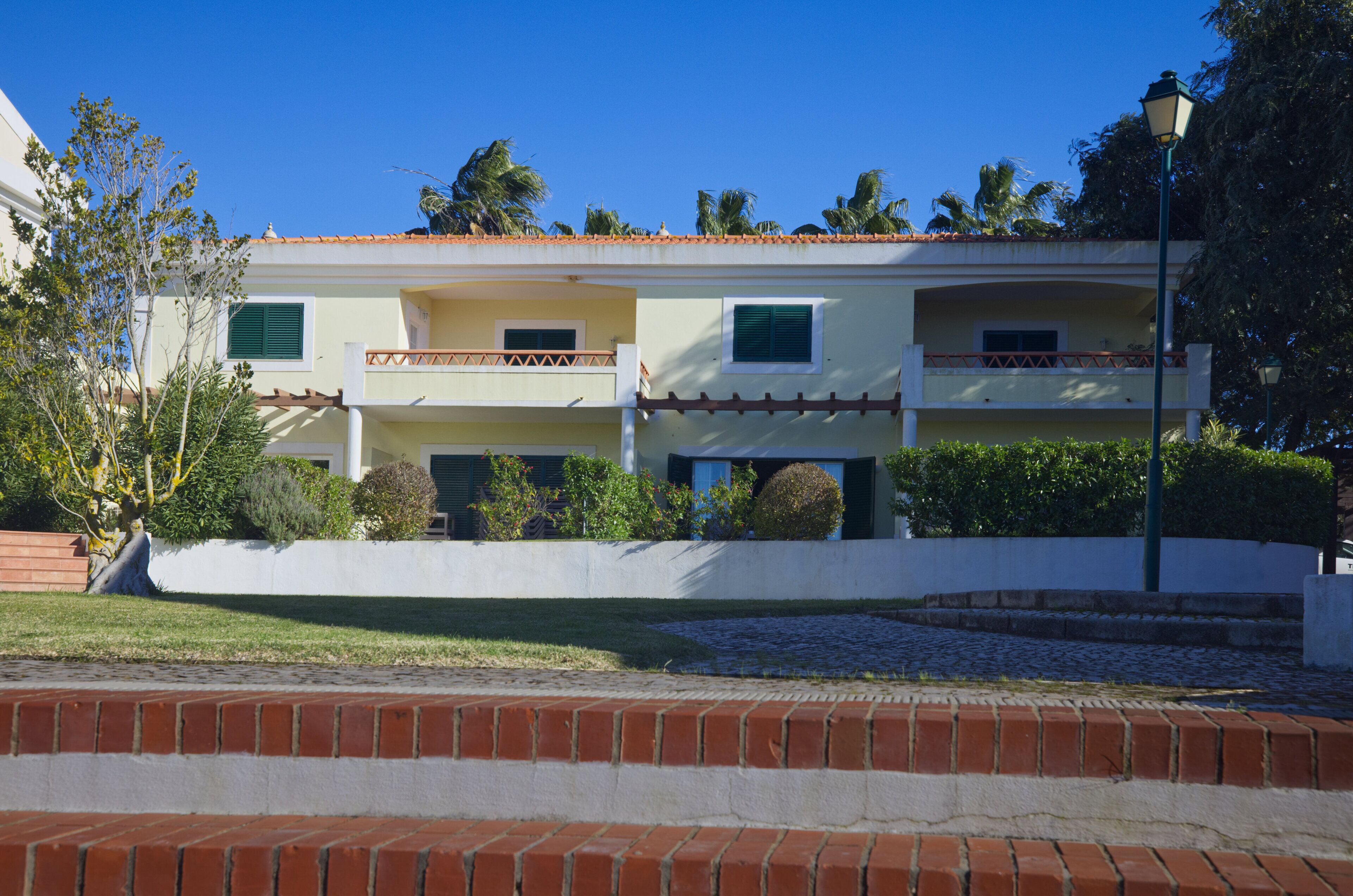 A two-story building with a flat roof, balconies, and a white exterior.