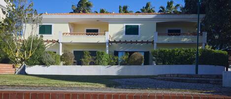 A two-story building with a flat roof, balconies, and a white exterior.