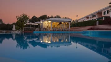 Una piscina al aire libre, sombrillas, tumbonas