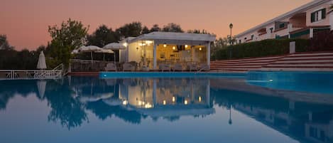 Una piscina al aire libre, sombrillas, sillones reclinables de piscina