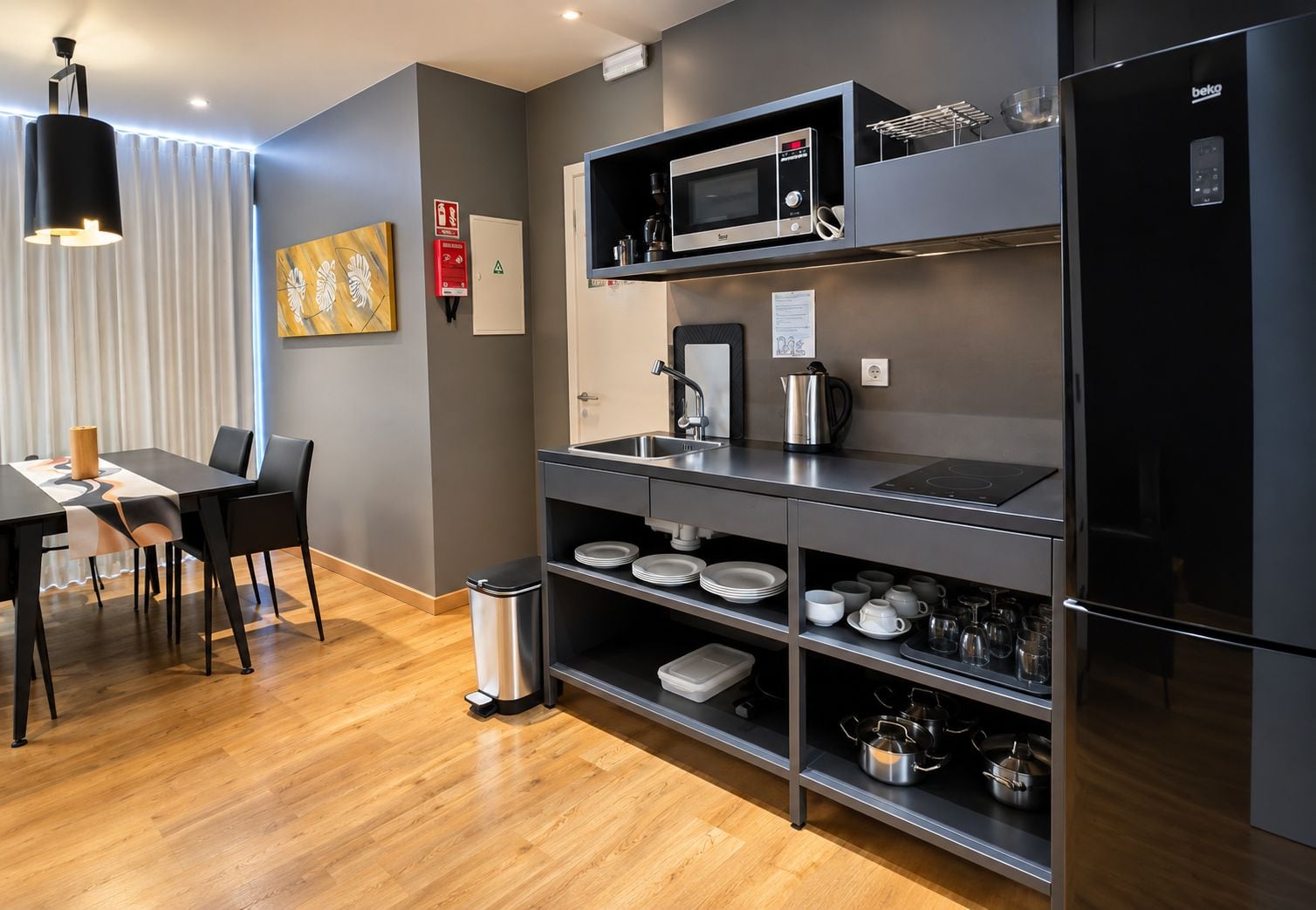 Una cocina moderna con microondas integrado, hervidor de agua y un refrigerador elegante.