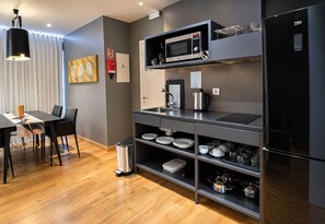A modern kitchen with a built-in microwave, kettle, and a sleek refrigerator. - Paraíso - Touristic Apartments (Funchal)