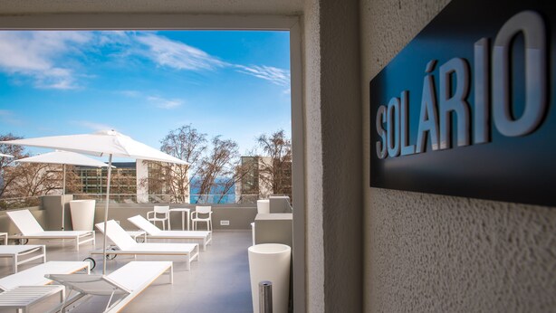 A rooftop lounge area with sun loungers, umbrellas, and a sign reading "SOLÁRIO". - Paraíso - Touristic Apartments (Funchal)