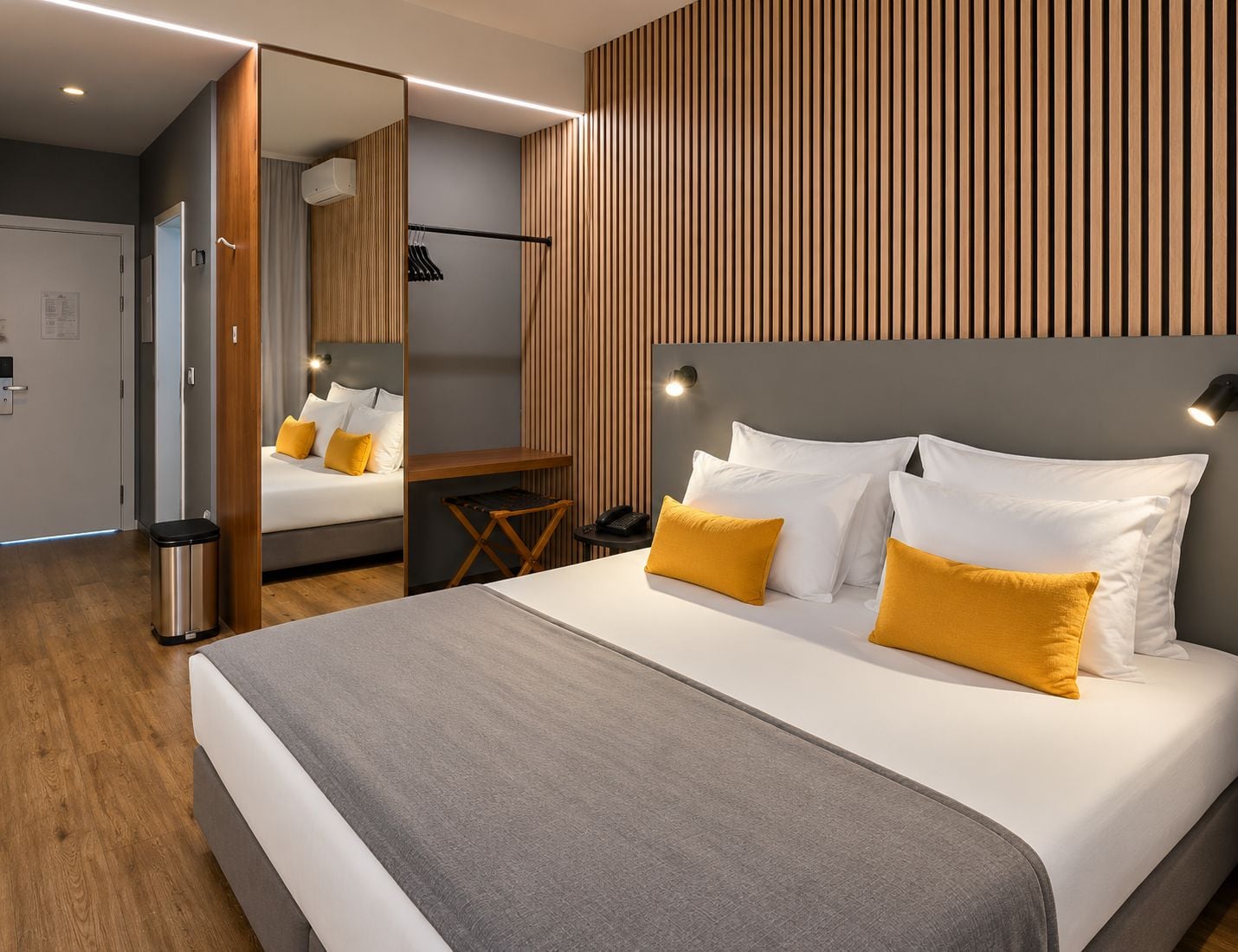 Una habitación de hotel moderna con una cama grande, un escritorio y un armario.