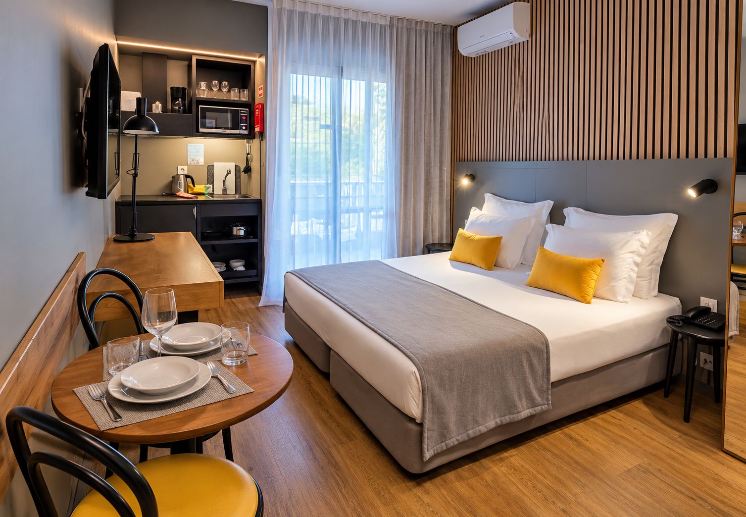 Habitación de hotel con cama, mesita de noche y zona de comedor con mesa y sillas.