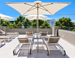 Terraza en la azotea con sillas de descanso, mesas y sombrillas, con un letrero de Vidamar Resorts al fondo.
