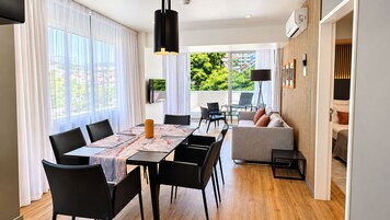 Un comedor moderno con una mesa dispuesta para seis personas, un sofá y vistas a zonas verdes.