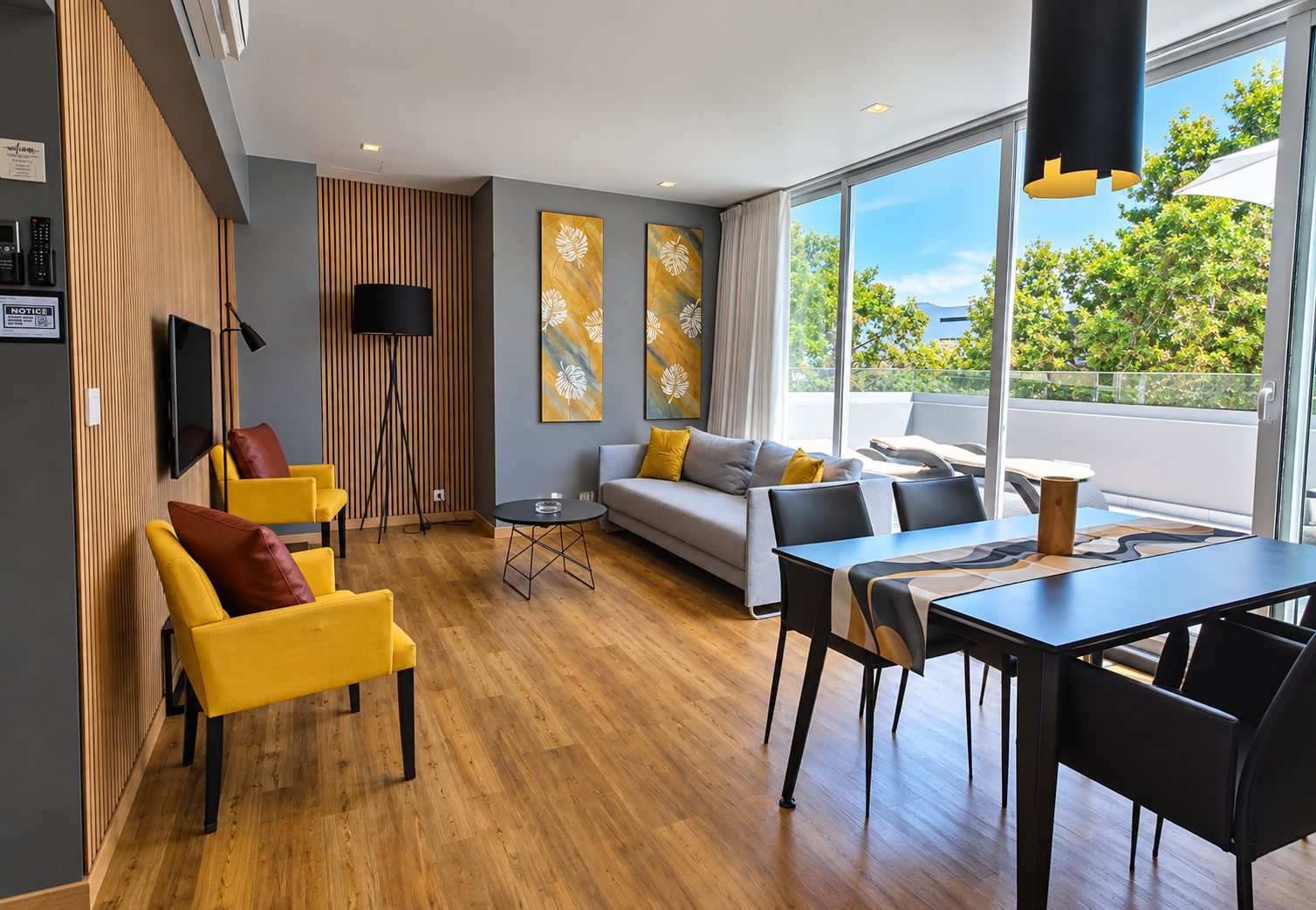 Ein modernes Wohnzimmer mit einer Couch, Sesseln, einem Esstisch und Kunstwerken an den Wänden.