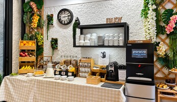 Un bufé de desayuno con un reloj, una cafetera y un cartel que dice 'ENJOY'.