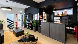 A modern hotel lobby with a reception desk, seating area, and a staircase. - Paraíso - Touristic Apartments (Funchal)