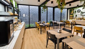 A modern restaurant with a counter, tables, chairs, and a view through large windows. - Paraíso - Touristic Apartments (Funchal)