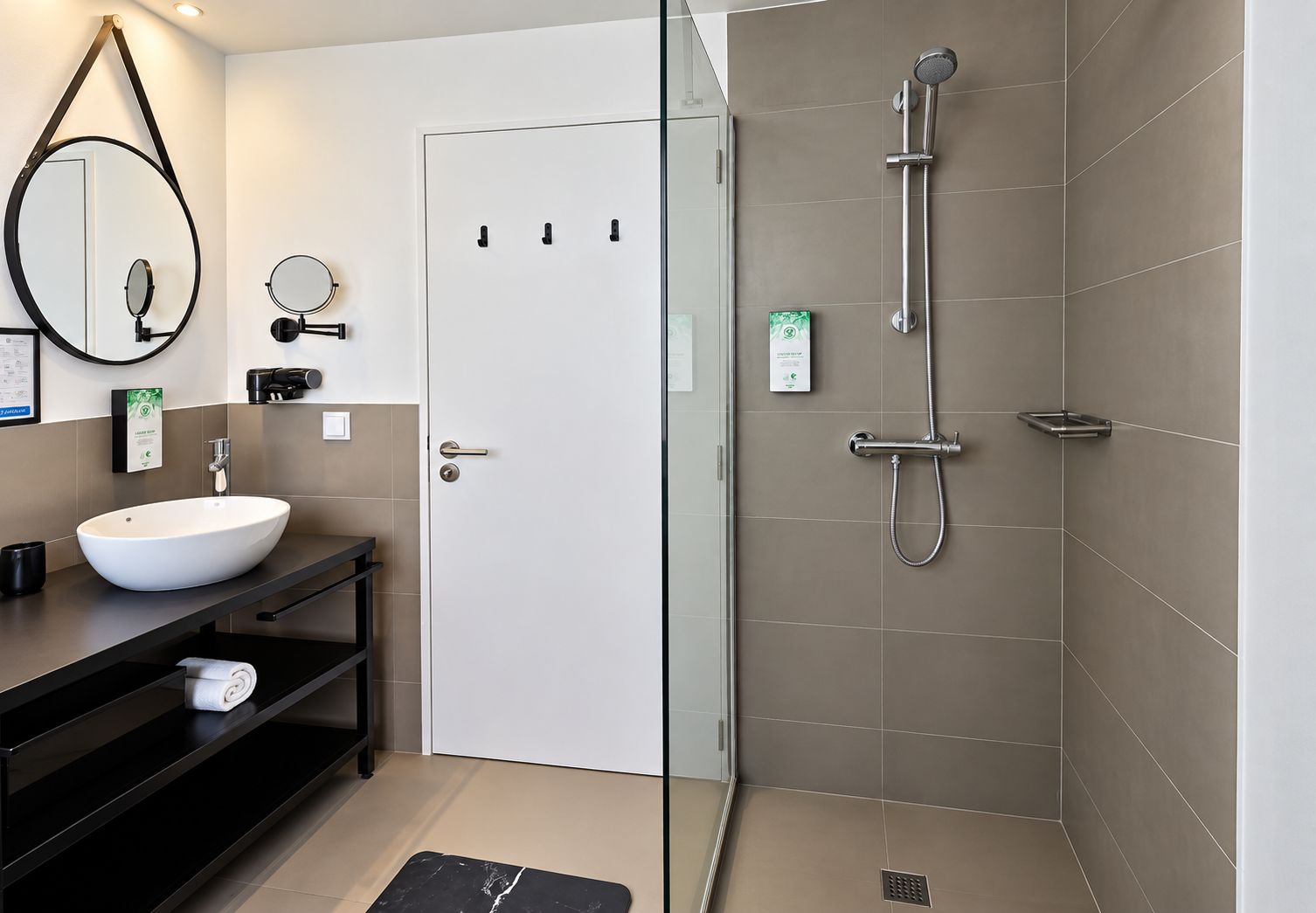 Un bagno moderno con un lavandino bianco, un mobile contenitore nero e una cabina doccia in vetro.
