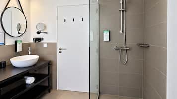 Un bagno moderno con un lavandino bianco, un mobile contenitore nero e una cabina doccia in vetro.