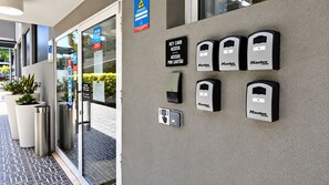Entrada de un hotel con puerta de vidrio, un cartel que indica acceso con tarjeta y varios dispositivos Master Lock para el acceso a las habitaciones.