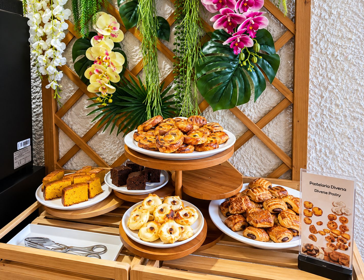Una mesa de buffet con diversos pasteles y postres, incluyendo croissants y hojaldres, dispuestos sobre soportes de madera.