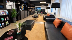A modern hotel lobby with a reception desk, seating area, and a view of the city. - Paraíso - Touristic Apartments (Funchal)