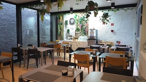 A restaurant with multiple tables and chairs, a coffee machine, and various plants. - Paraíso - Touristic Apartments (Funchal)