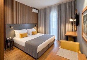 A modern hotel room with a large bed, a bedside table, a desk, and a chair. - Paraíso - Touristic Apartments (Funchal)