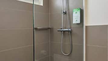 Ducha moderna con puerta de vidrio, cabezal de ducha de mano y panel de control en la pared.