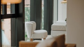 Un interior moderno con ventanas amplias, un sillón blanco y un reposapiés a juego.
