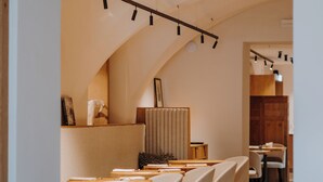 Un comedor moderno con una larga mesa, múltiples sillas y un techo alto con iluminación en riel.