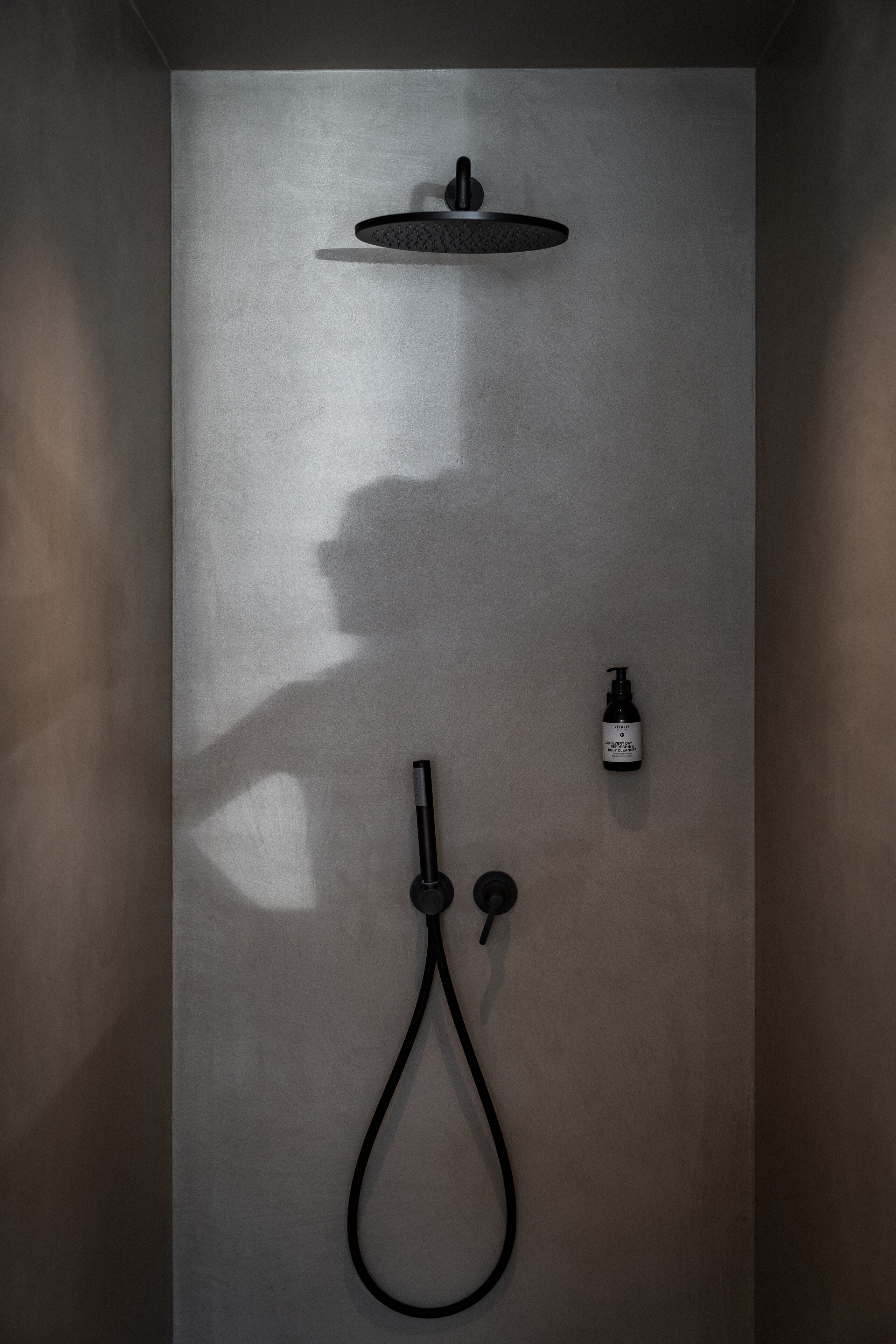 Eine moderne Dusche mit Handbrause und am Wand montiertem Wasserhahn.