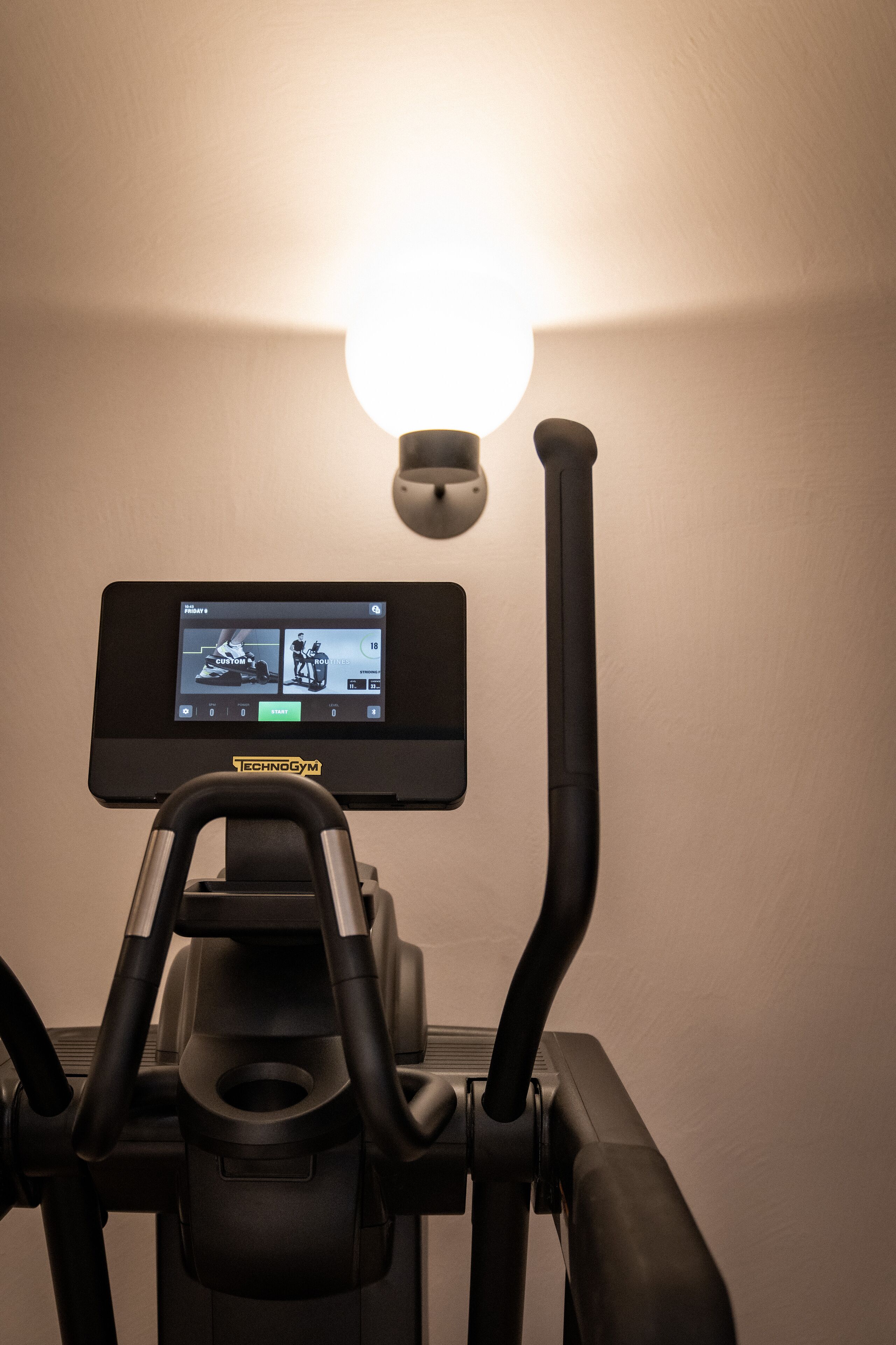 A stationary bike with a digital display and a light fixture above it.