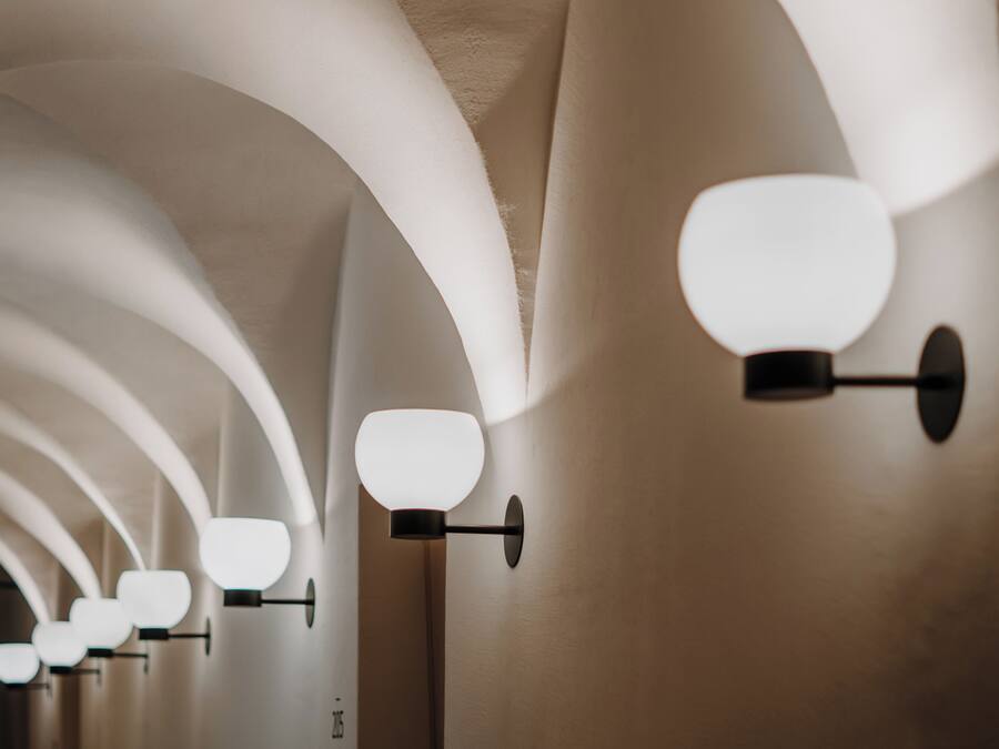 A series of wall-mounted light fixtures with a modern design, arranged in a linear pattern along a curved ceiling.