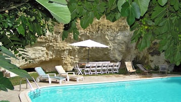 Una piscina al aire libre de temporada, sombrillas