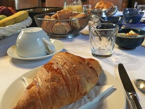 A breakfast setting with a croissant, a cup, a glass, and various bowls on a table. - Château de Ternay (Ternay)