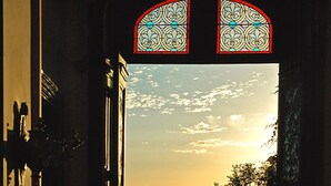 An open doorway leading to a view of a sunset over a landscape with trees and hills. - Château de Ternay (Ternay)