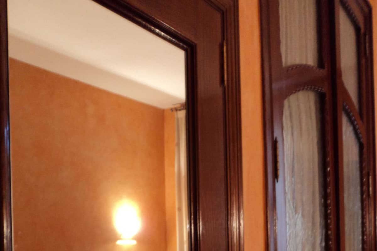 A hotel room with a bed, a nightstand, and a wall-mounted lamp.