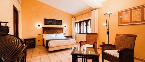 A hotel room with a bed, a piano, a table, and two chairs.