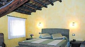 A bedroom with a large bed, two bedside tables, a nightstand, a window with curtains, and a wooden ceiling. - L'Àgora Hotel (Bocairente)