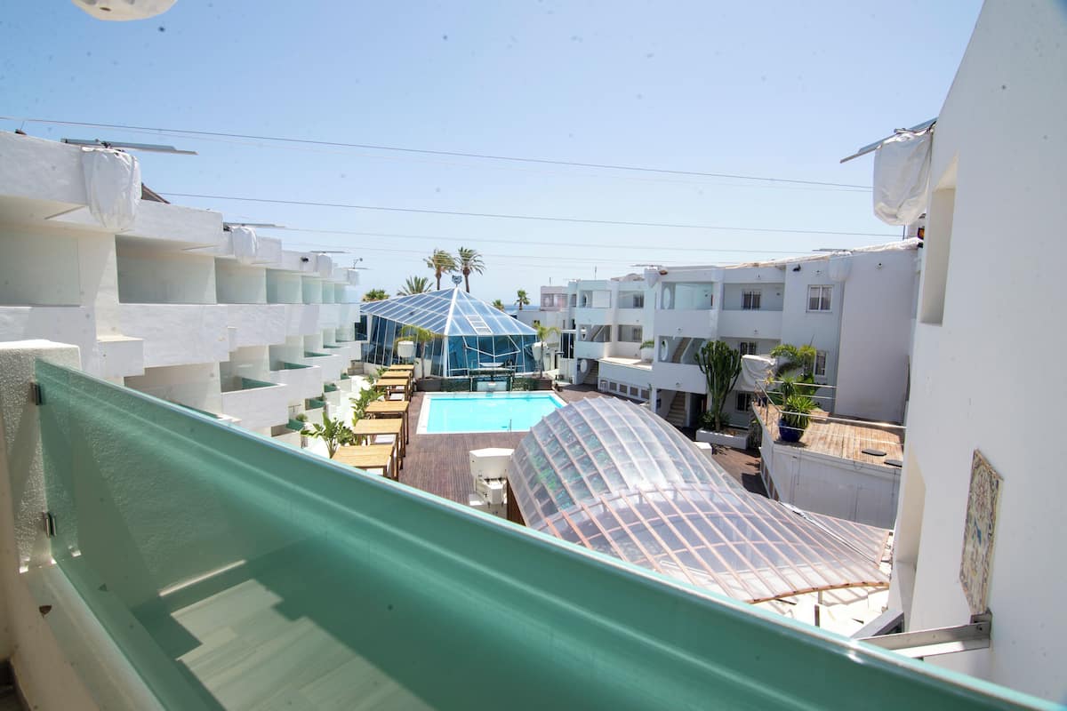 Zona residencial con piscina, un porche cubierto y edificios blancos.