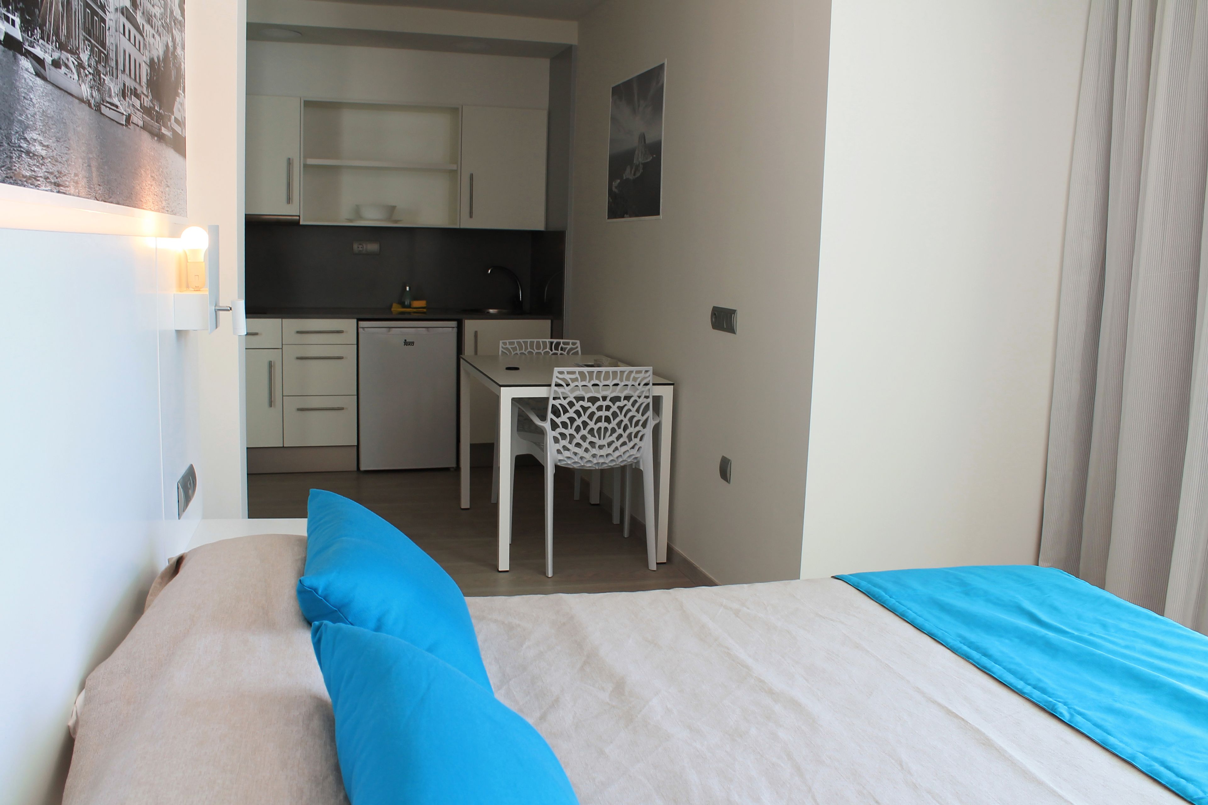 Une chambre avec un lit, un bureau et une chaise, située dans un petit coin cuisine.