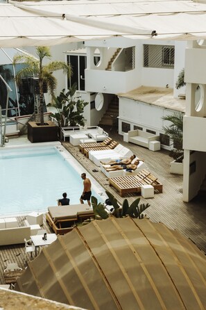 Un área de piscina en la azotea con sillones de descanso y una piscina.