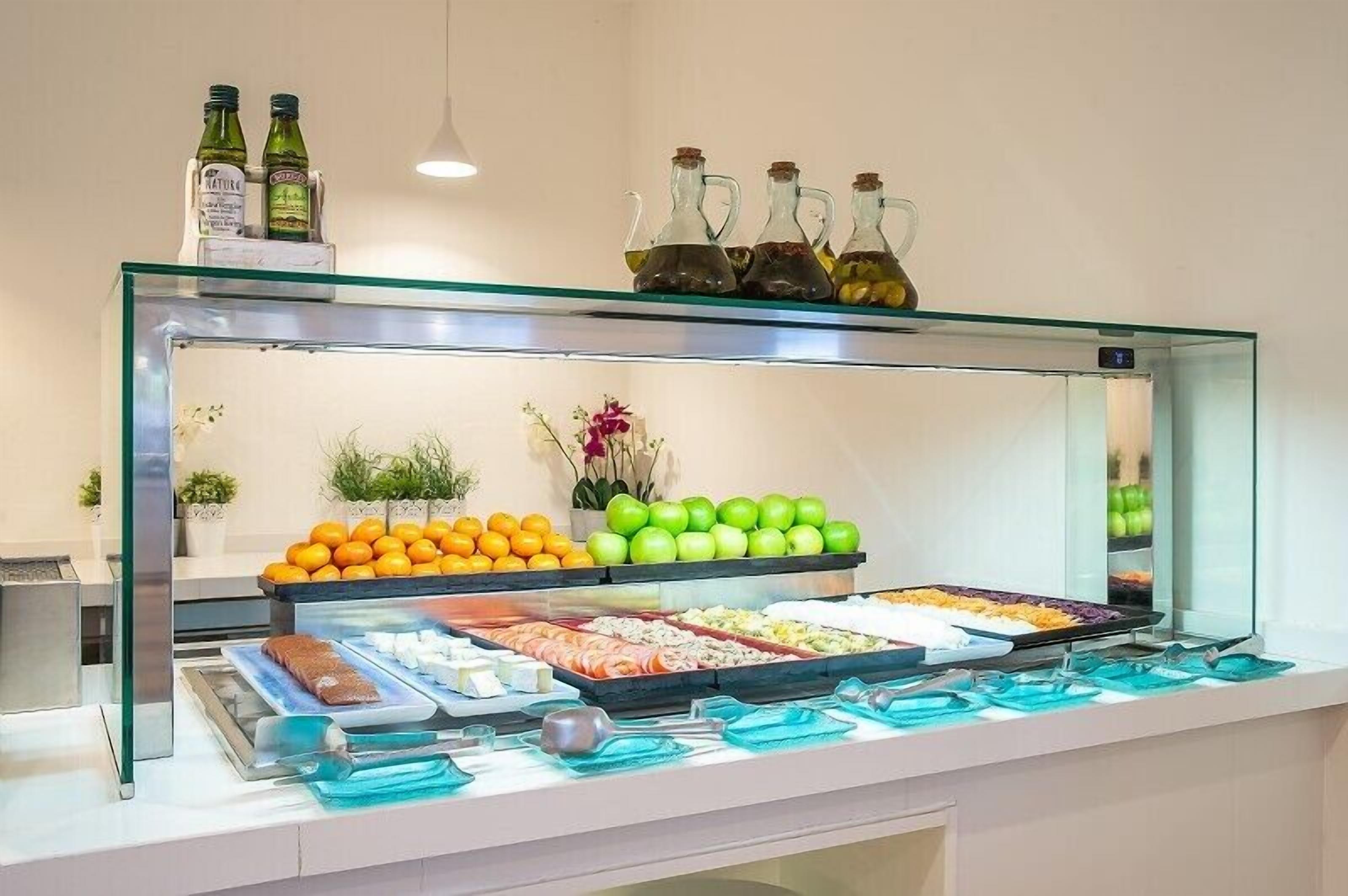 A buffet with various food items, including fruits, vegetables, and meats, displayed in a glass case.