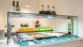 A buffet with various food items, including fruits, vegetables, and meats, displayed in a glass case.