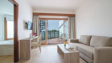 Una sala de estar moderna con sofá, una mesa de centro, un televisor montado en la pared y un balcón con vistas.