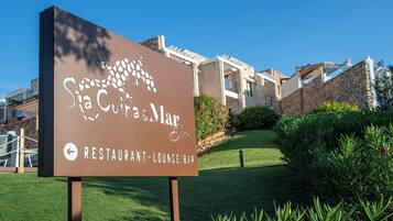 A sign for "Sia Cuca Mar Restaurant-Lounge Bar" with a clear view of the building in the background.