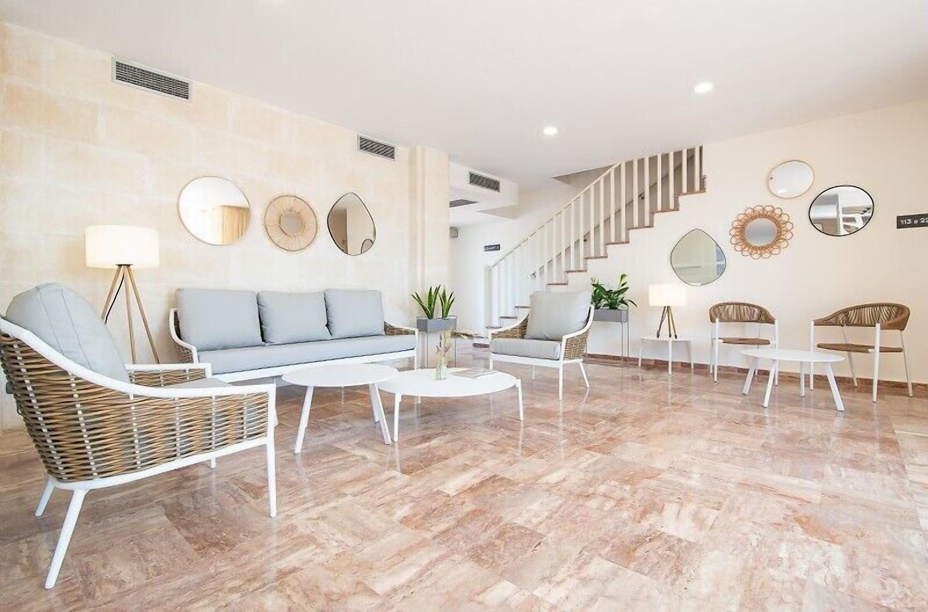 Una sala de estar moderna con un sofá, dos sillones, una mesa de centro y una escalera.