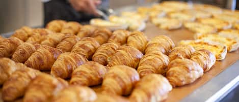 A bakery display with croissants and pizzas.