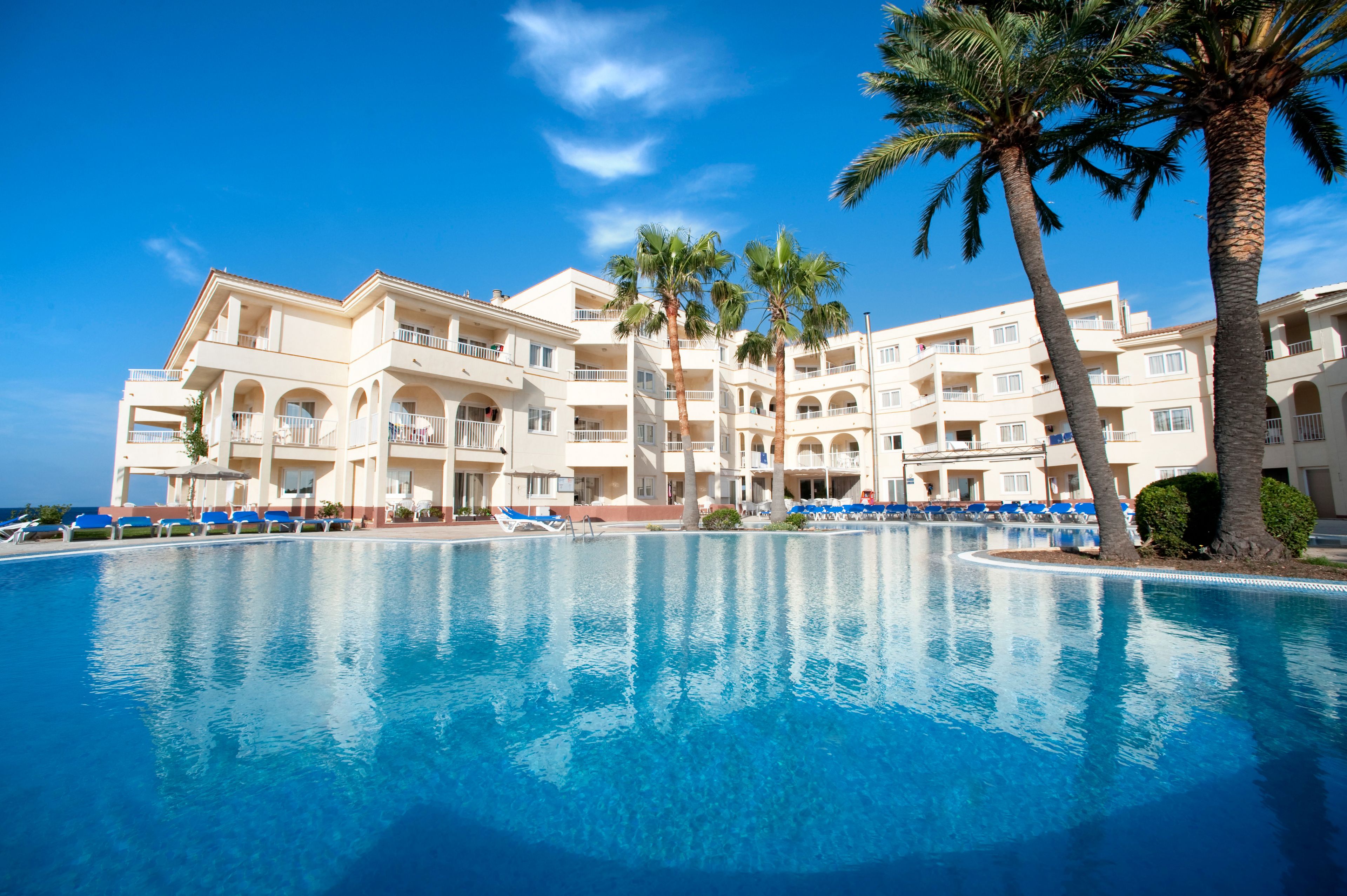 Una piscina al aire libre, sombrillas, sillones reclinables de piscina