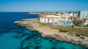 A coastal hotel with a pool area, multiple balconies, and a view of the sea. - Grupotel Tamariscos (Ciutadella de Menorca)